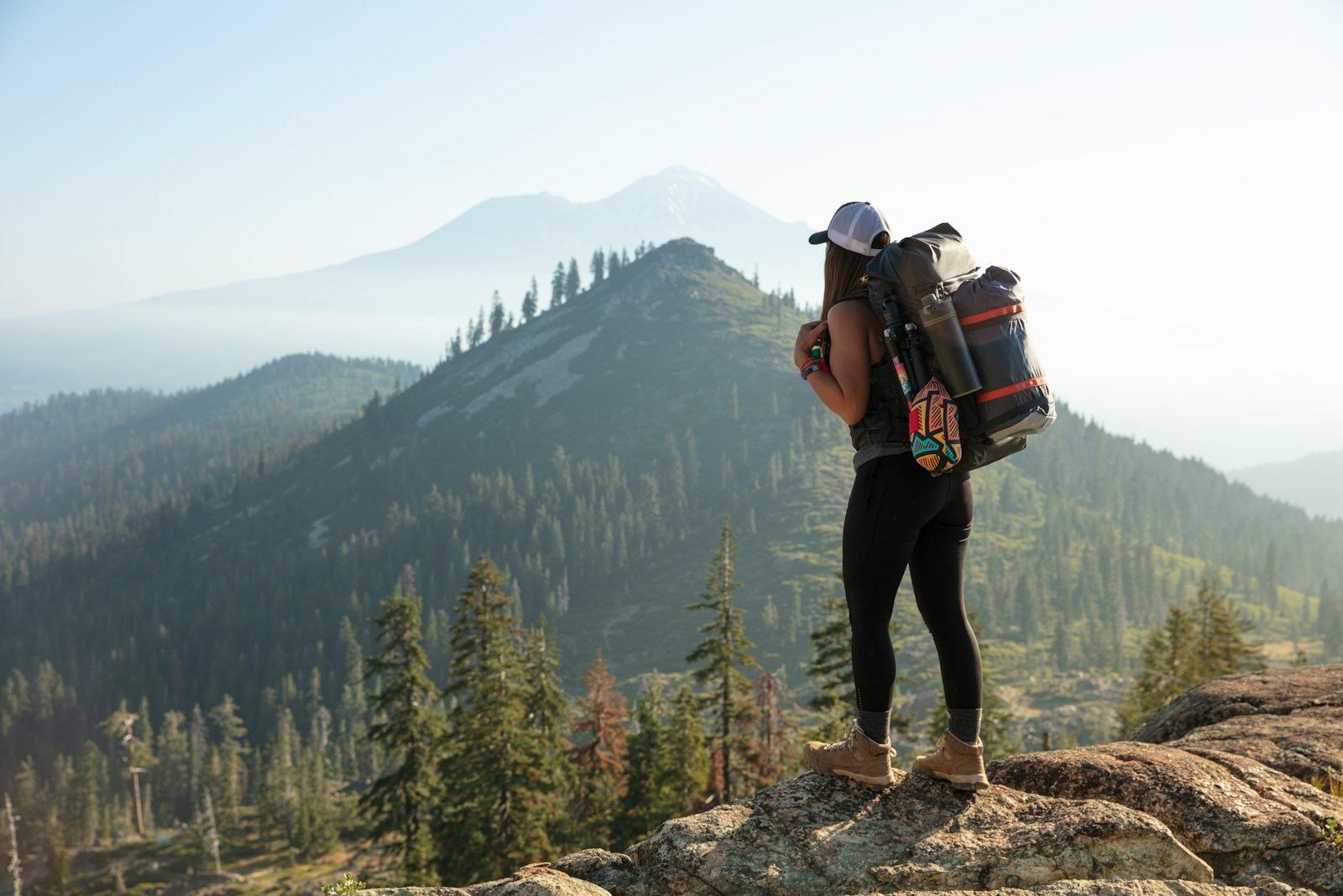 person in black jacket and black pants wearing black backpack standing on rocky mountain during daytime hiking