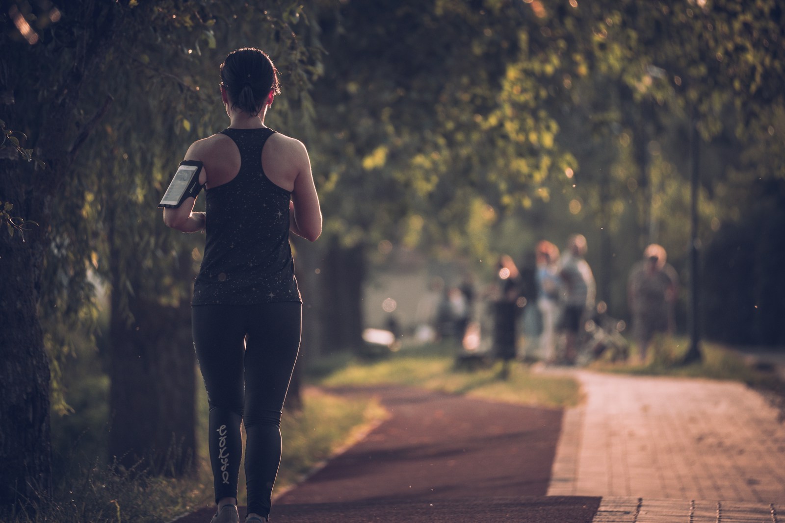 woman in black tank top and black pants running on sidewalk during daytime