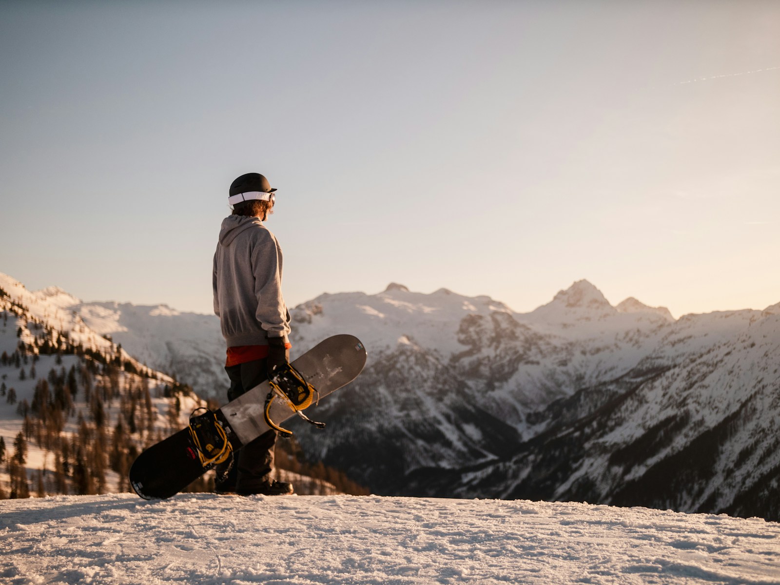 snowboarding man in white jacket and black pants standing on brown rock formation during daytime